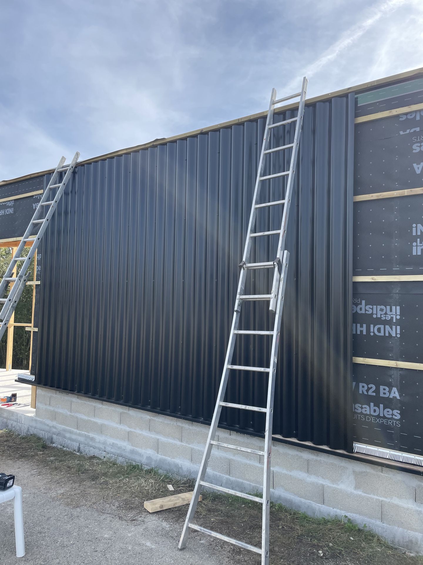 Photo de la pose du reste des panneaux du bardage en taule ondulée de la maison Le Triangle