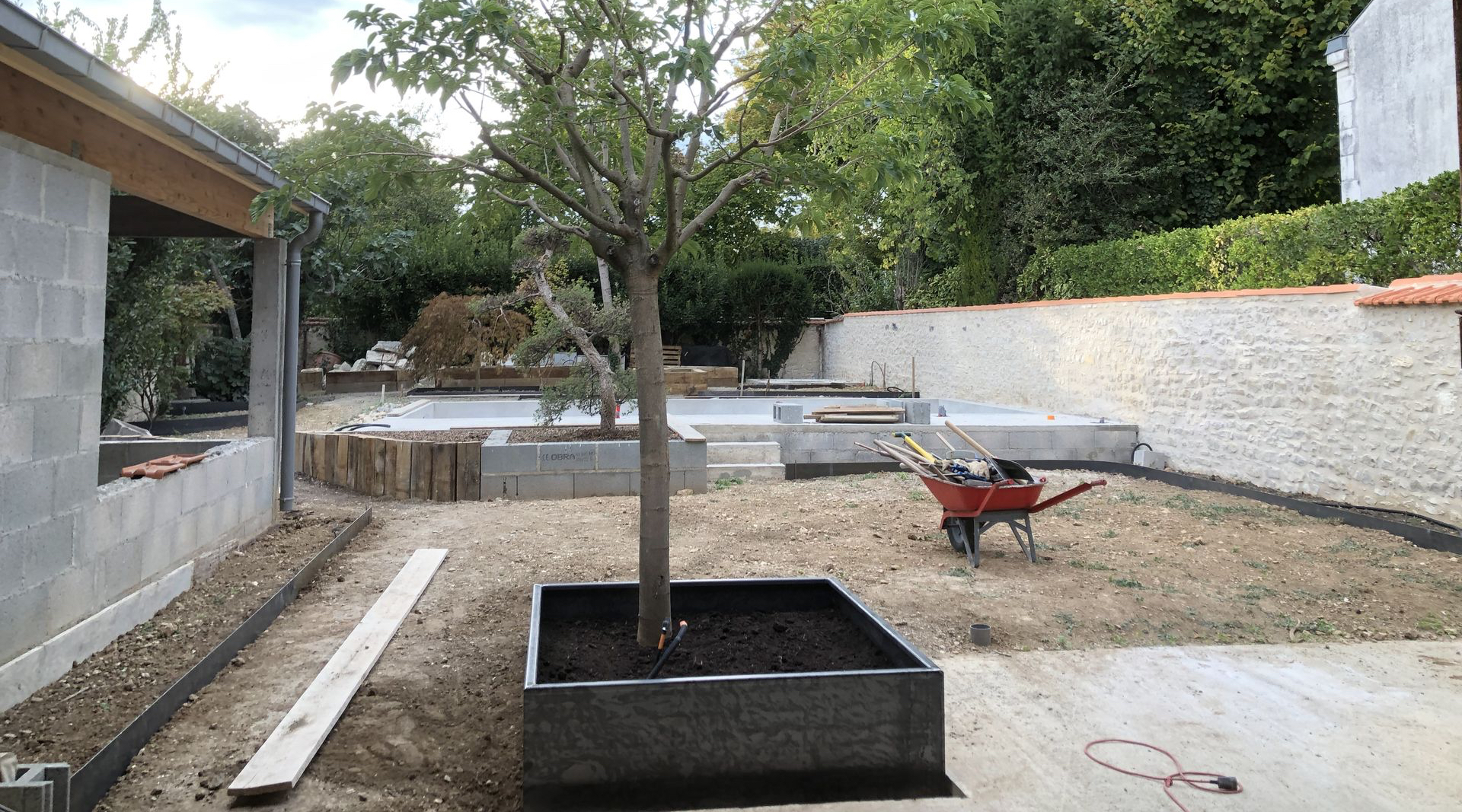 Photo du jardin et de la piscine en travaux depuis la salle à manger de la maison La Commanderie